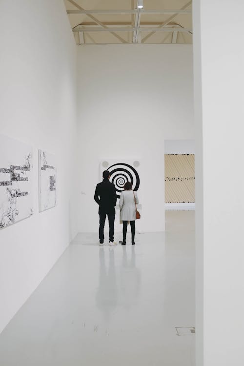 Art fair visitors examining works at gallery booths
