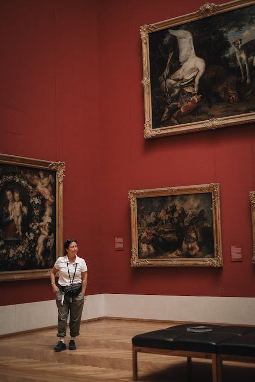 A collector studying a painting closely in a well-lit gallery space