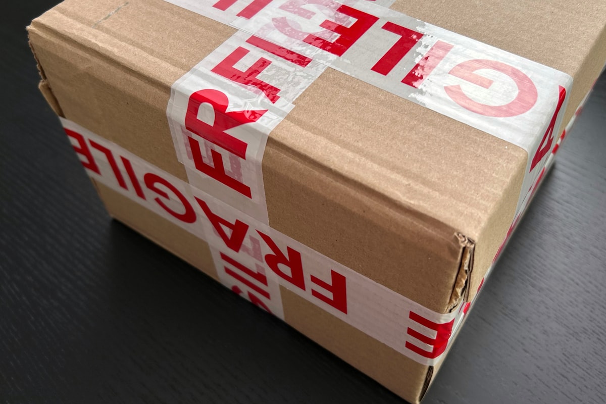 A framed painting being carefully wrapped in bubble wrap with foam corner protectors visible on each corner