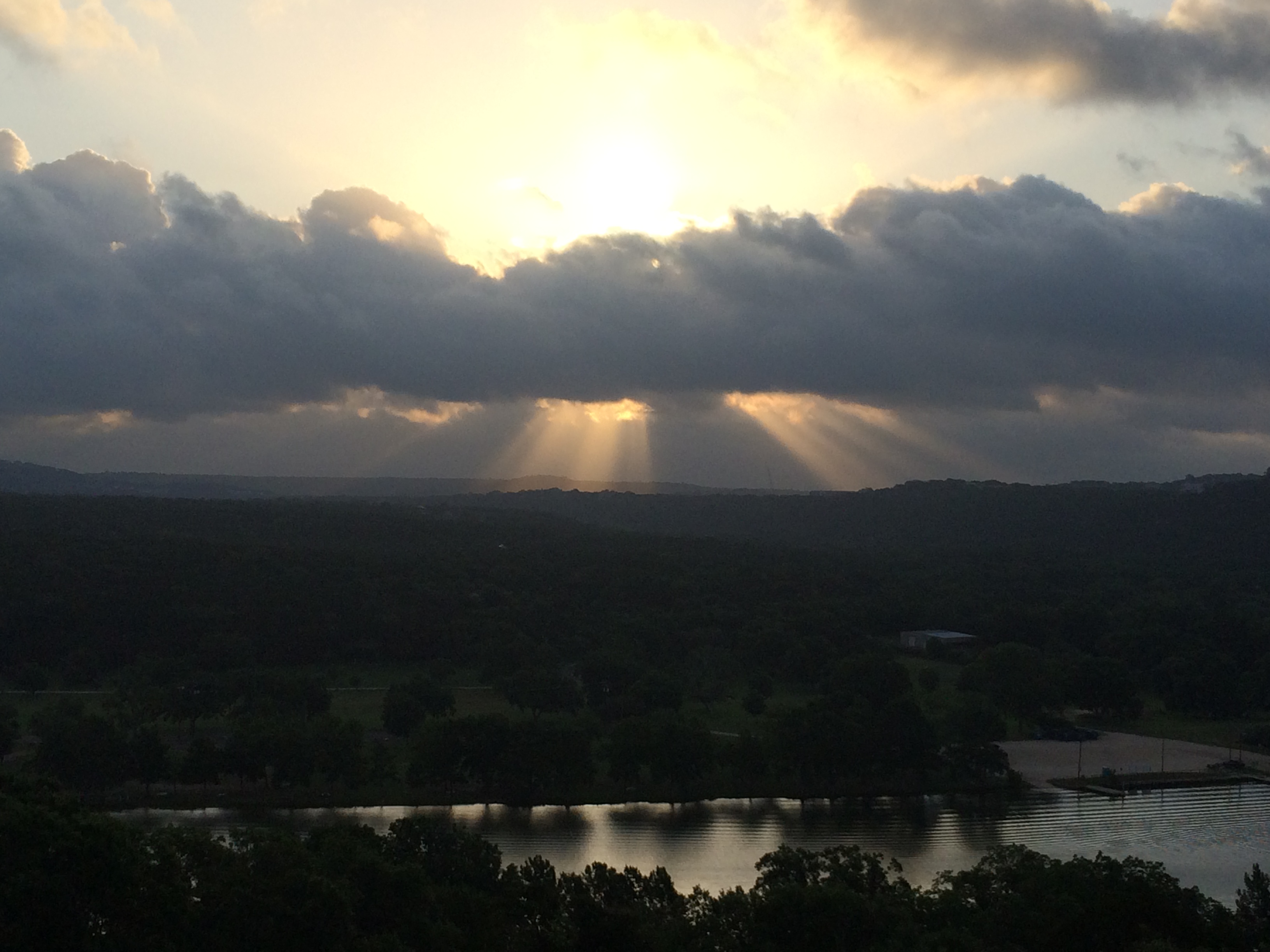 Sunlight beaming through clouds onto the Texas Hill Country landscape near Austin, home of Omni Barton Creek Resort